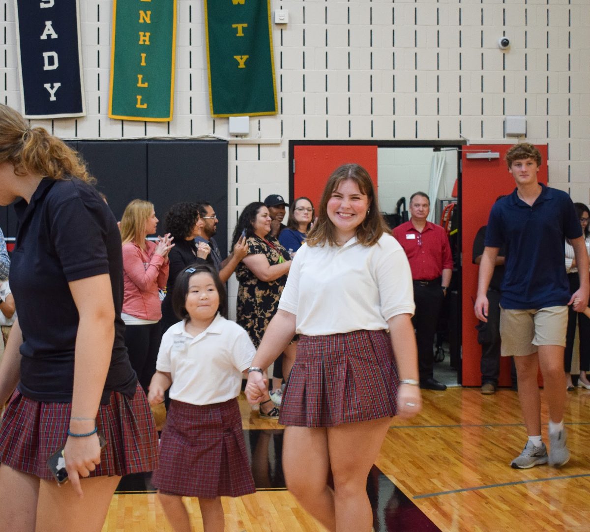 Senior Talulah Monthy celebrates her last first K-12 assembly with first grade student Rayna Wang. 