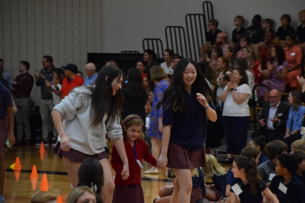 Seniors Elizabeth Hu and Ally Rodriguez skip with kindergartner Siena Herlihy at the first all-school assembly.
