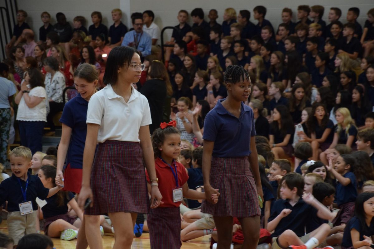 Seniors Dylan Davis and Zia Falasha lead kindergartner Victoria Hunt to her spot amidst cheers from the School.
